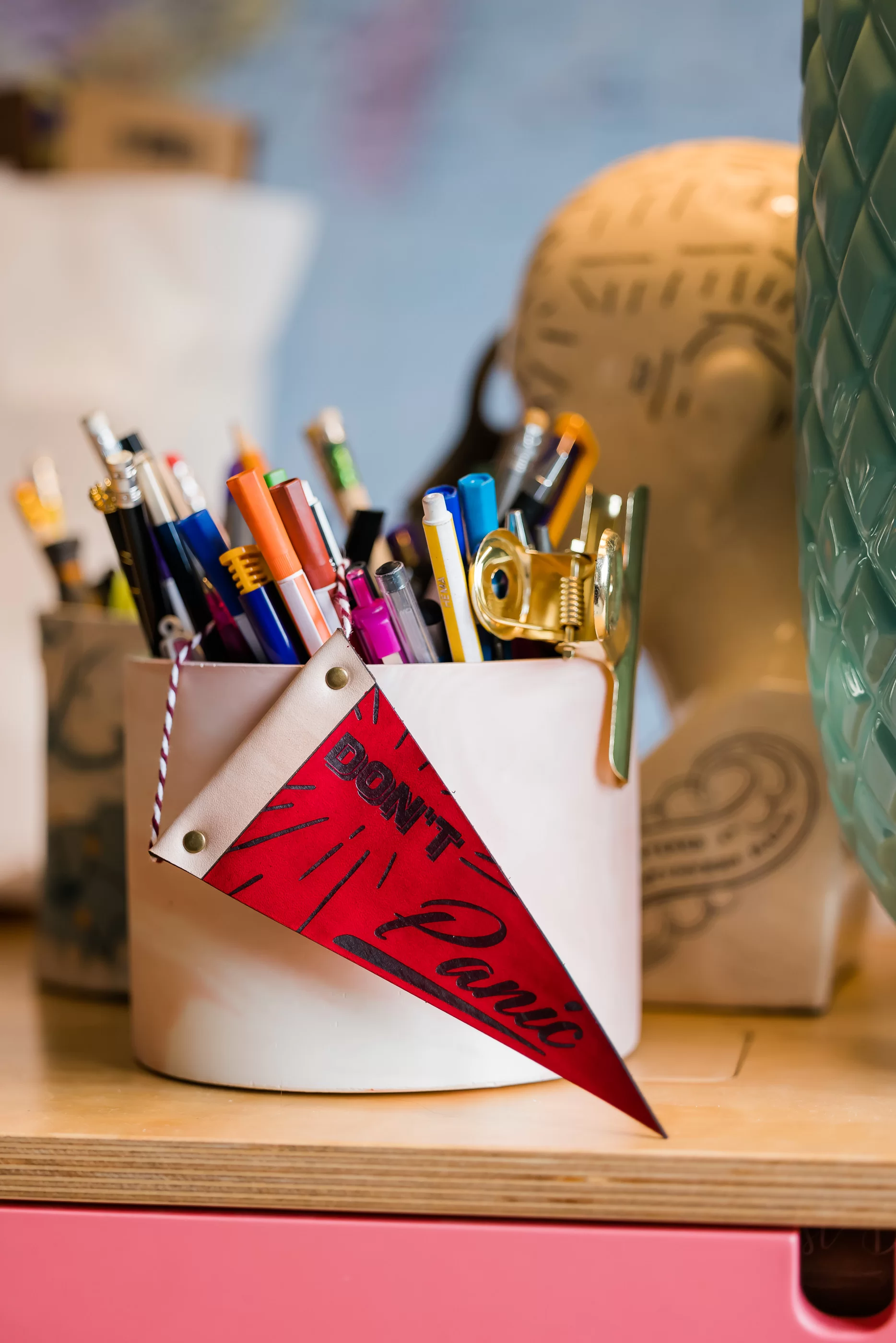 Red Don't Panic pennant hanging off some pens in a pen pot 