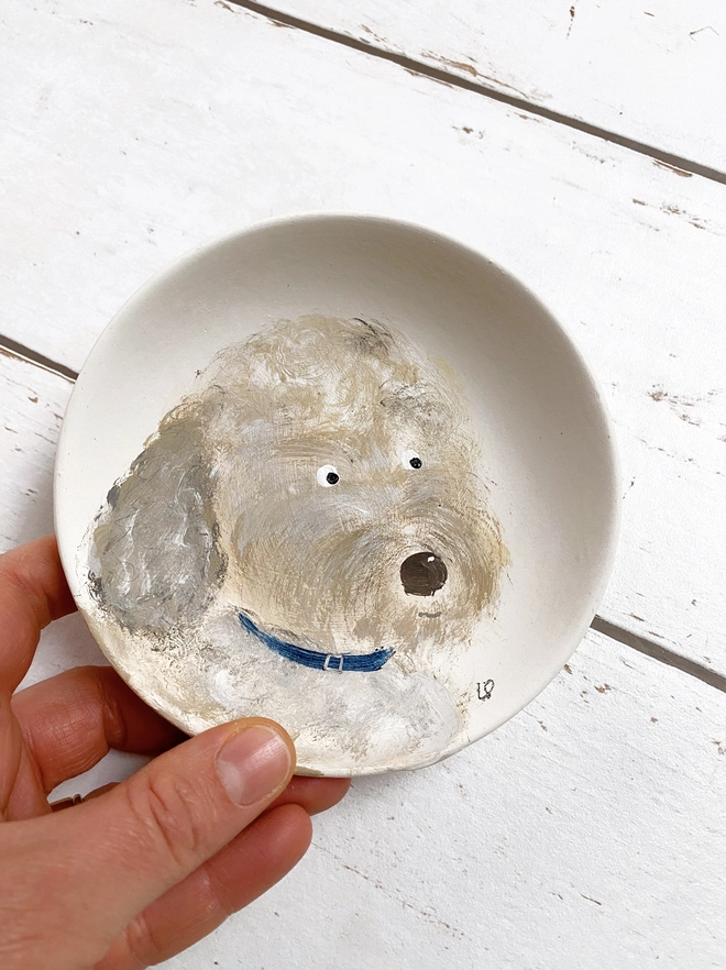 little plate painted with a dog being held in a hand