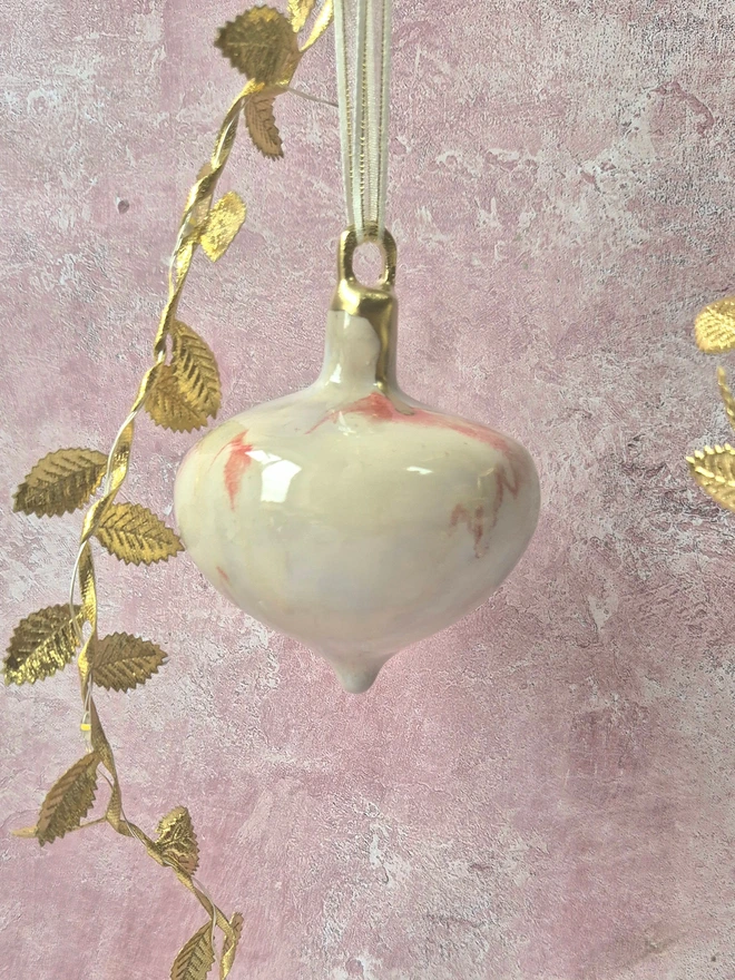 Ceramic christmas bauble decorations in a pearlescent glaze with white, cream and pink and gold, with silk ribbon and gold detailing. Photographed on a pearlescent serving dish with gold pears and christmas lights, gift, christmas, ceramics, pottery, christmas, decorations, christmas tree