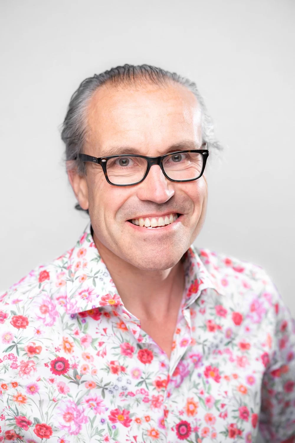 Will Ramsay, founder of the Affordable Art Fair, smiling at the camera in a white and pink floral shirt.