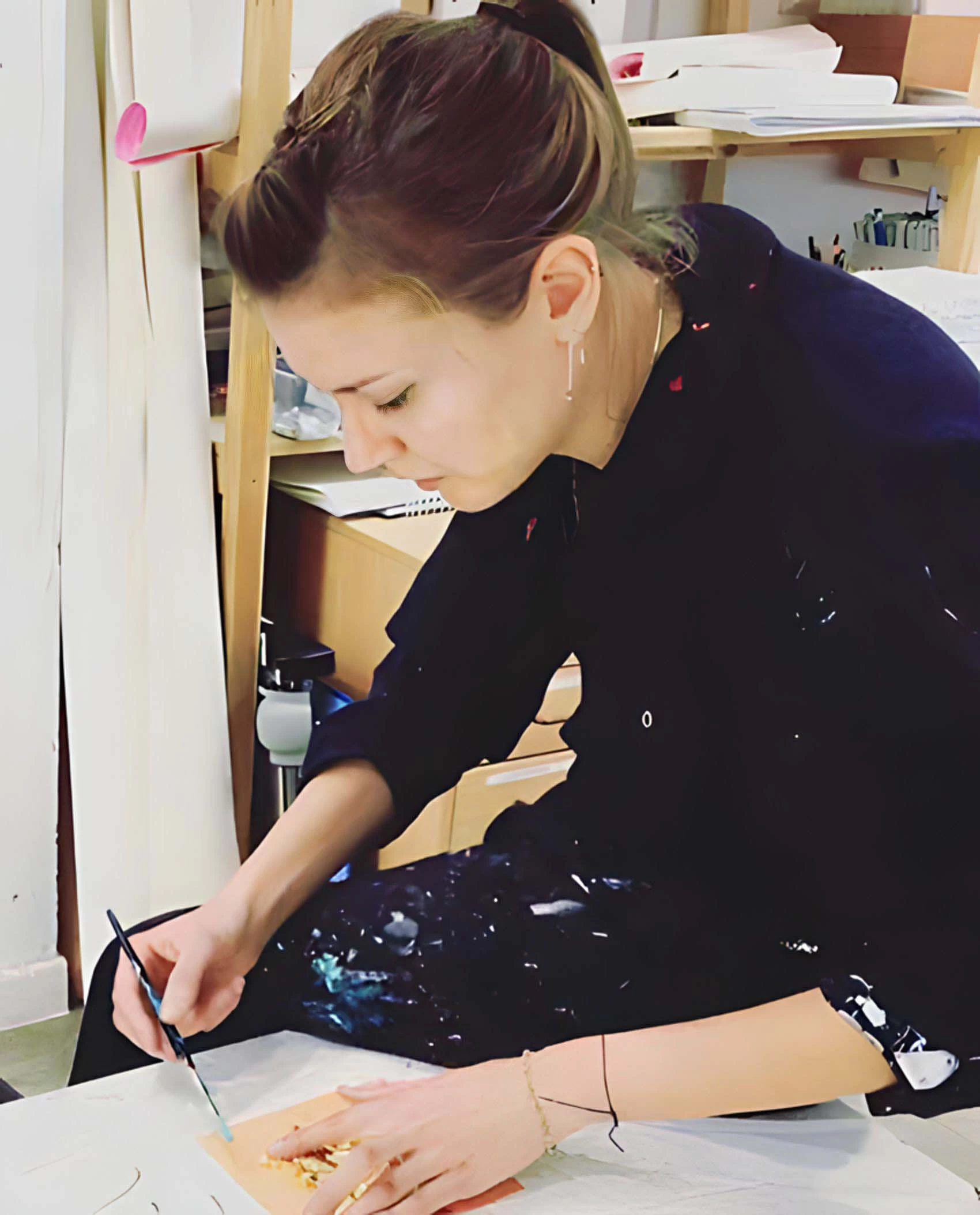 Fiona biddington sits in her studio and adds gold leaf to some work