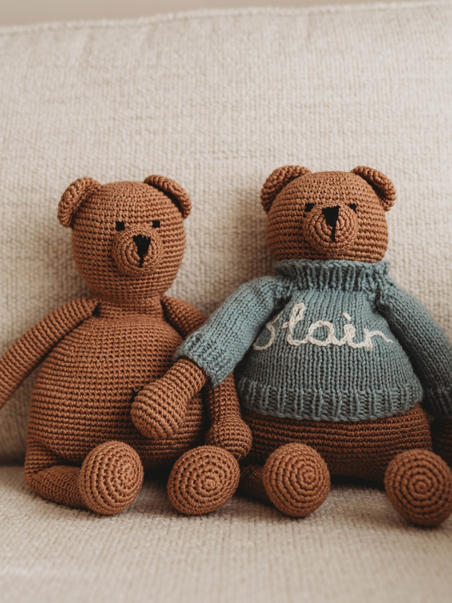 two hand crochet brown teddy bears on beige sofa with hand knit personalised jumper