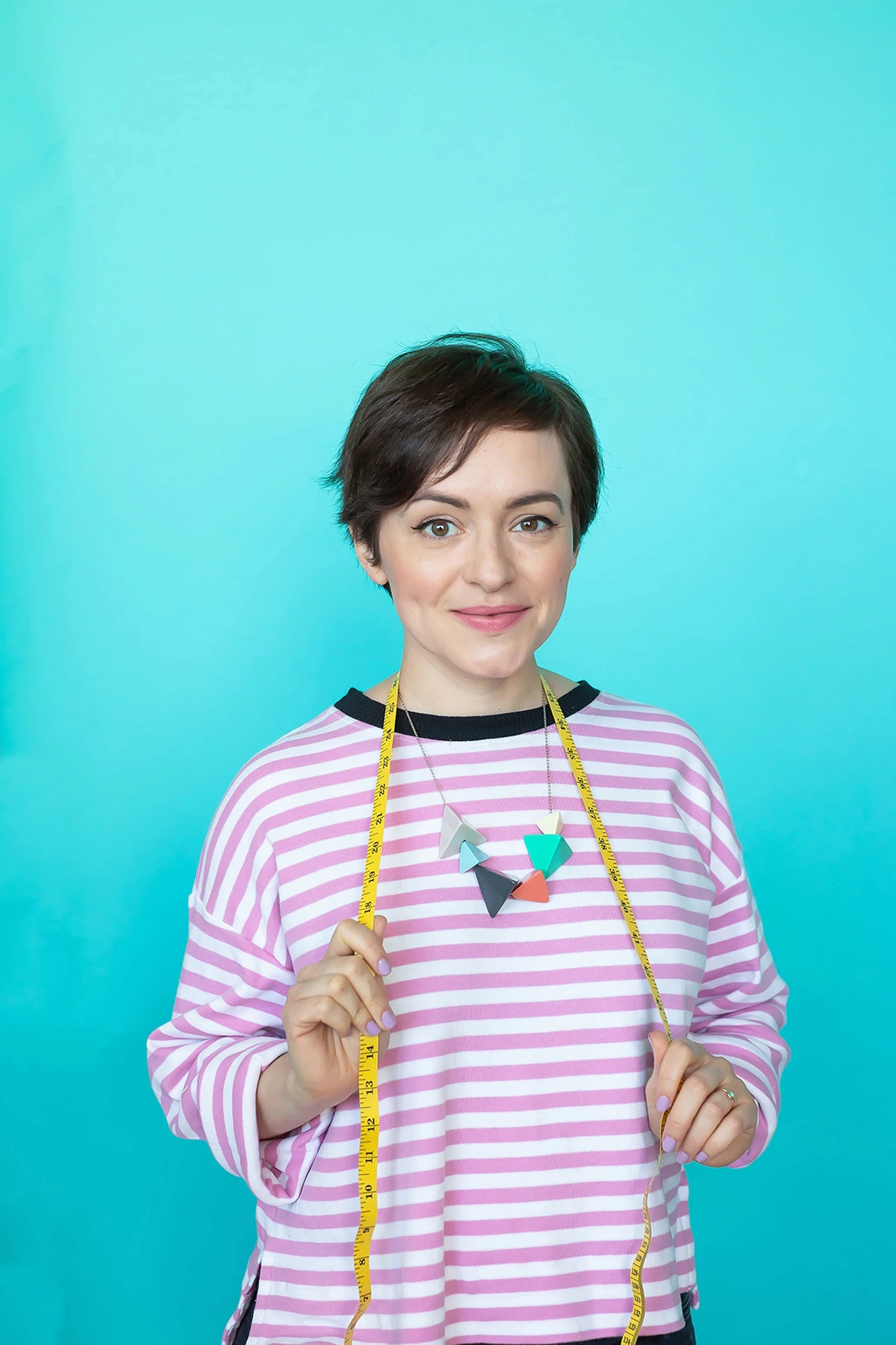Tilly Walnes, founder of Tilly and the Buttons, smiling at the camera, stood infront of a blue background. 