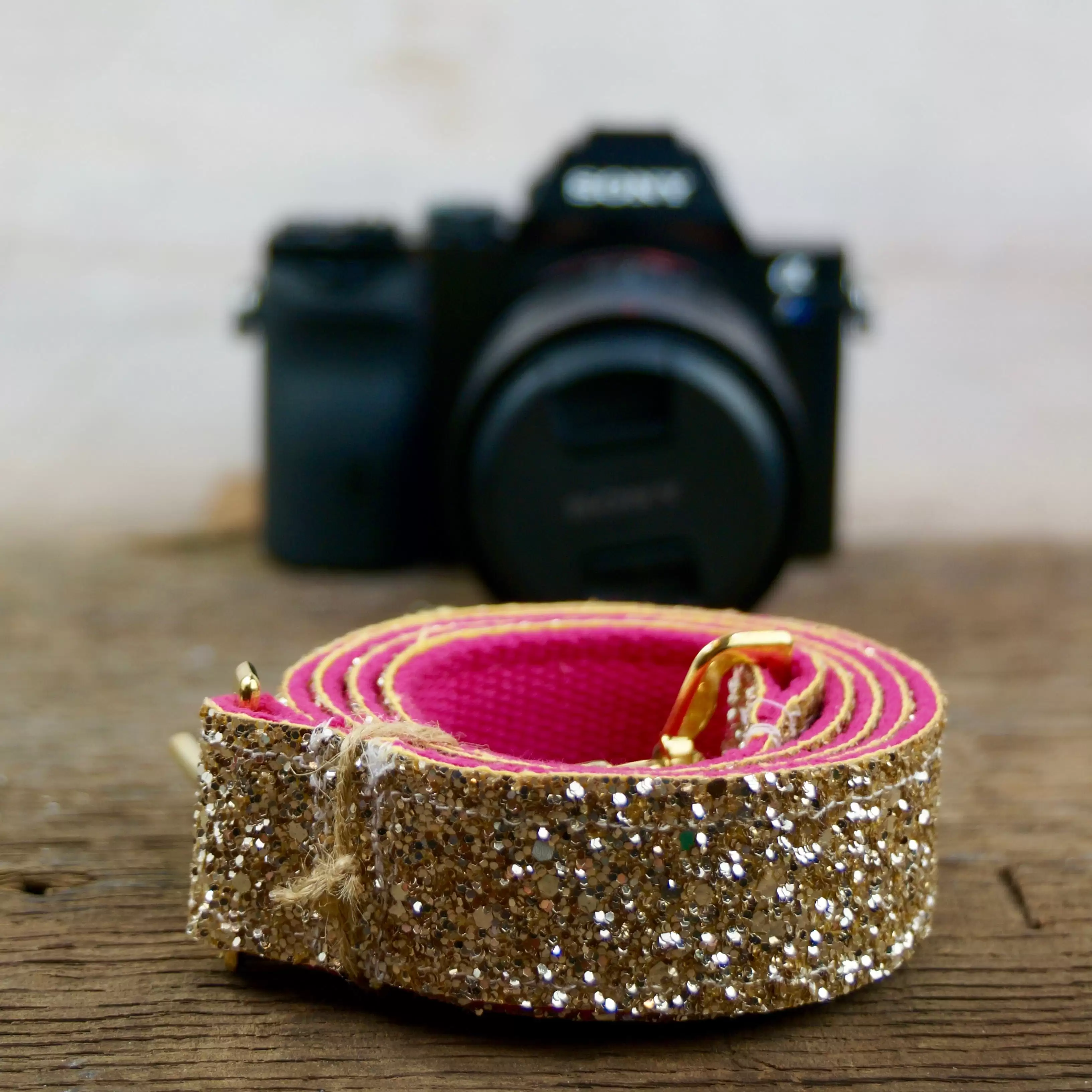 Camera with a gold sparkly belt on a wooden table