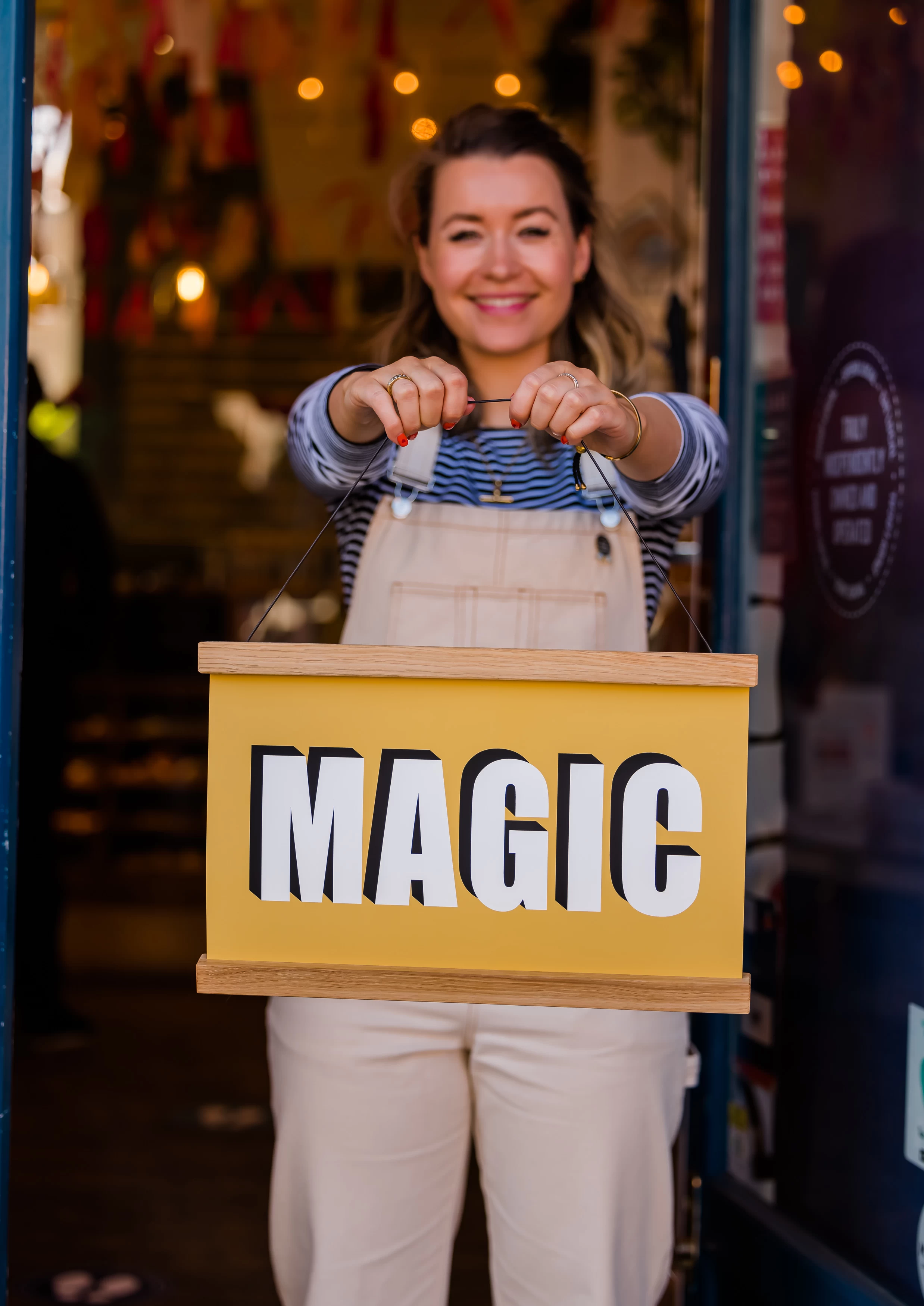Woman holding yellow illustrated sign with the word magic on it 
