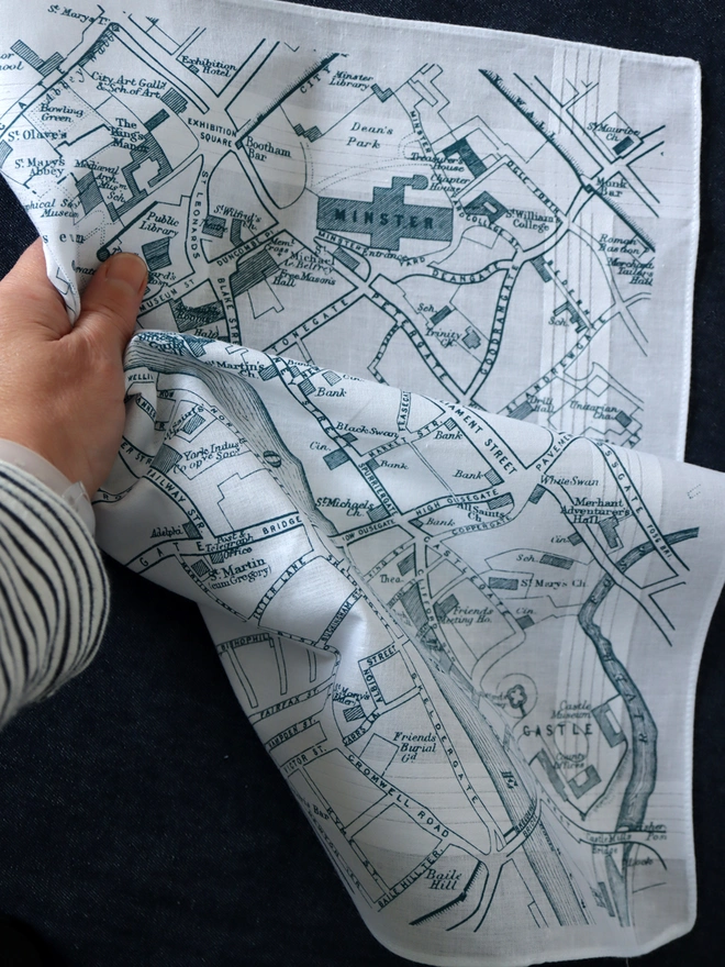 Mr.PS York map handkerchief held by a white hand and a stripy top on a dark background