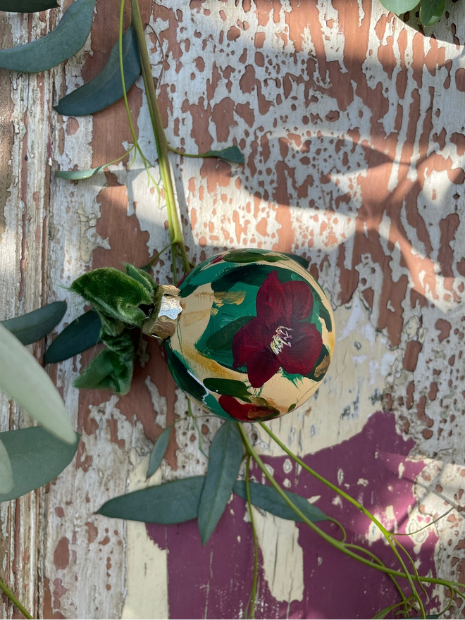 hand painted floral Christmas bauble dark cream background adorned with deep red hellebore flowers