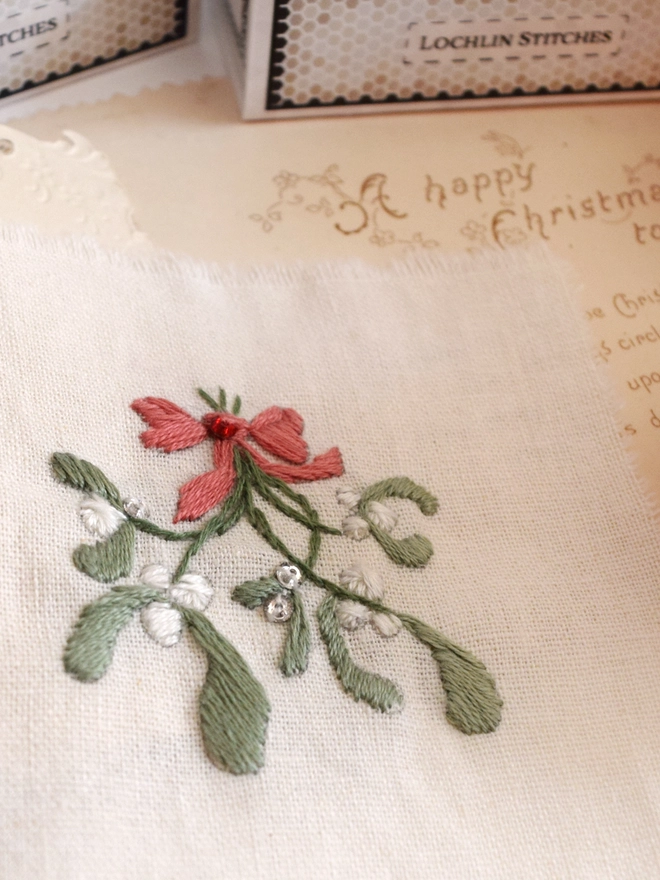 A sprig of mistletoe with white berries and a red bow. A few crystals are attached.