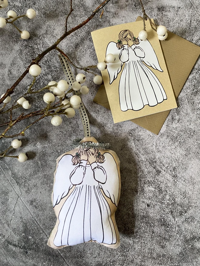 angel Christmas tree decoration laid next to a matching angel greeting card laid on a Kraft envelope