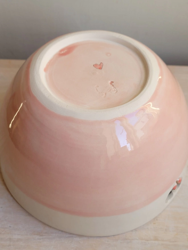 a pink bowl showing the base with the potters stamp and handpainted red heart