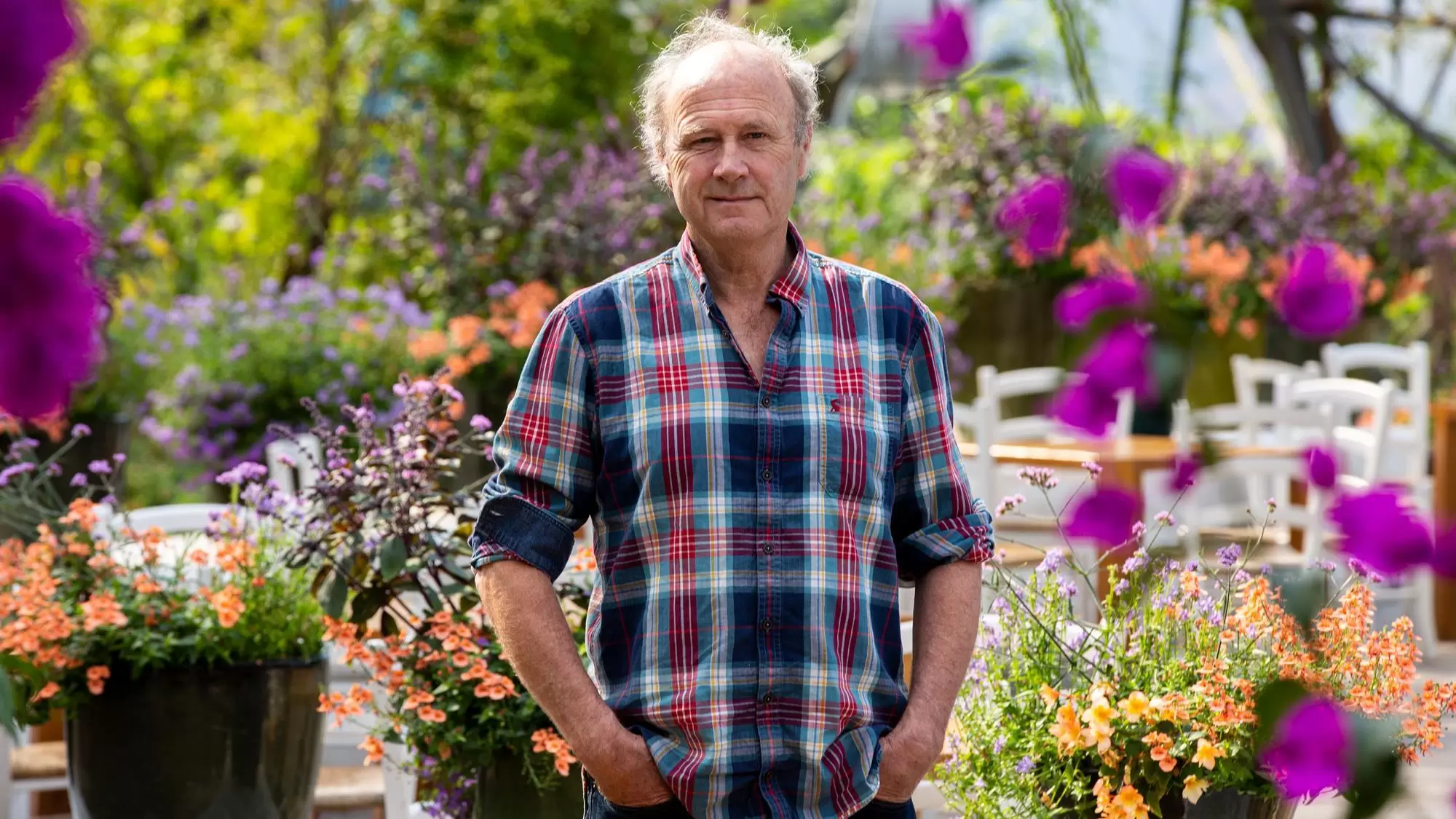 Sir Tim Smit KBE, founder of The Eden Project, smiling at the camera, wearing blue and red checkered shirt.