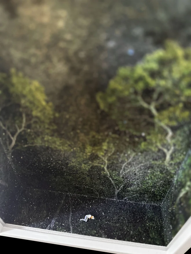 Miniature scene in an artbox showing a tiny woman sleeping in a sparkling night forest