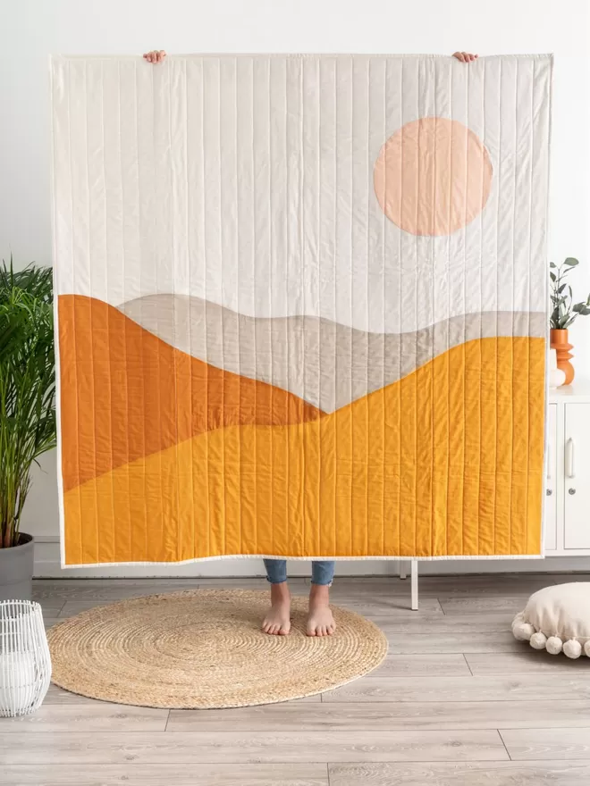 Desert Quilt Being Held Up in Living Room