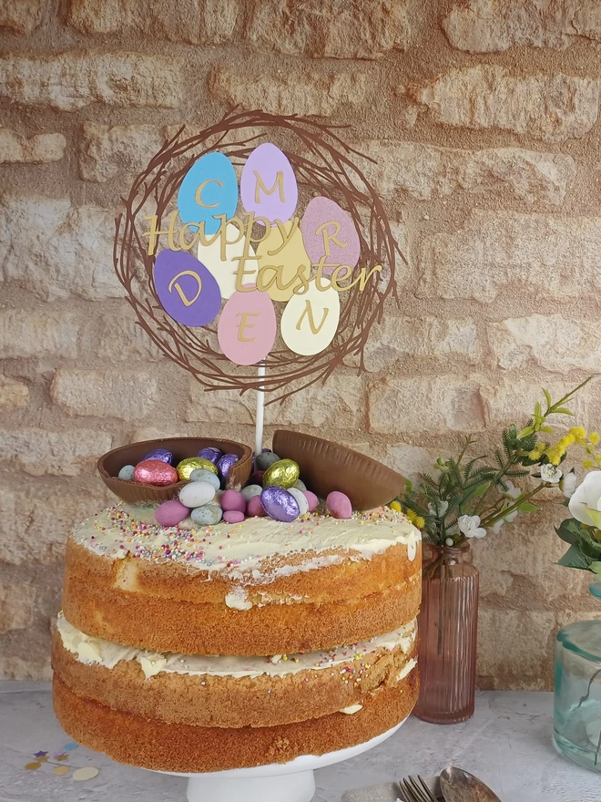 Easter cake topper placed in the centre of a large sponge cake decorated with easter eggs