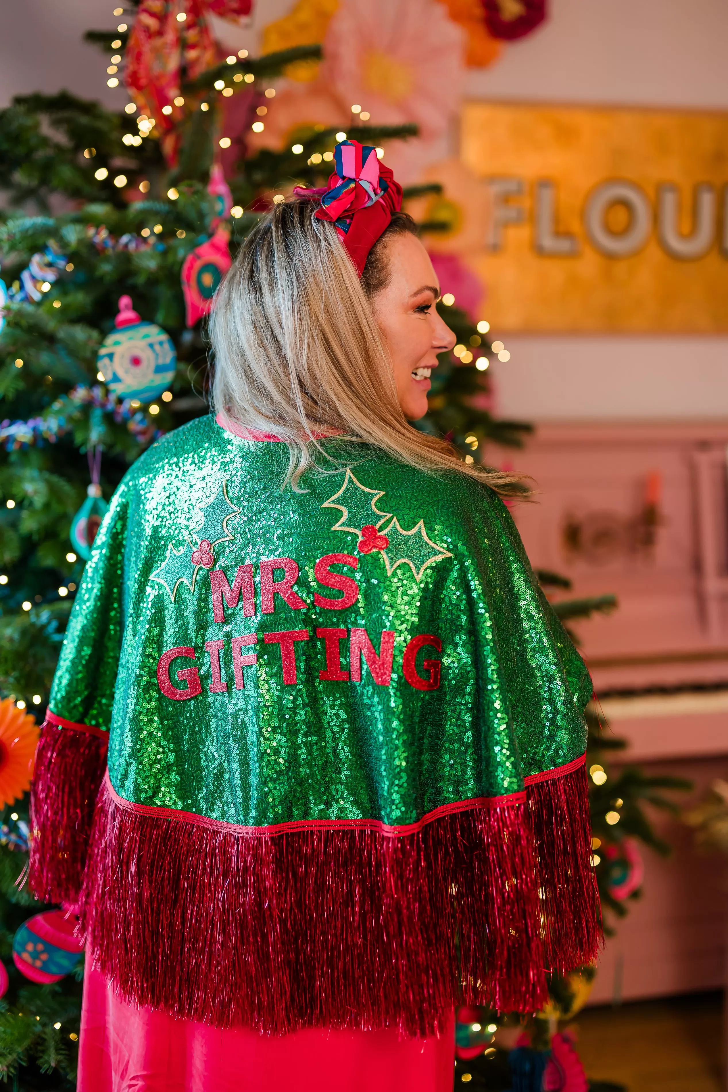 Holly wearing the Mrs Gifting Cape in front of a Christmas tree