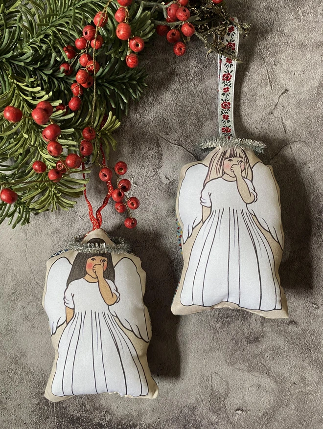 2 little angels sucking their thumbs hung on a Christmas tree branch with red berries