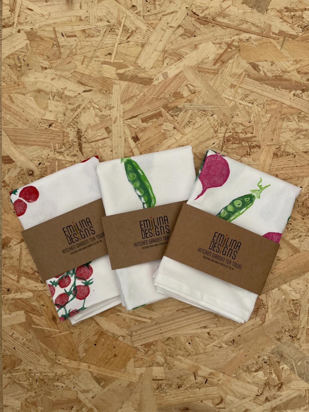 three white tea towels with veggie patterns, and brown label wraps