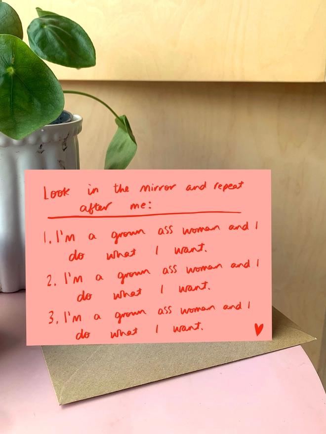 Card sits on side table with plant. Card reads 'Look in the mirror and repeat after me: I'm a grown ass woman and I do what I want.'