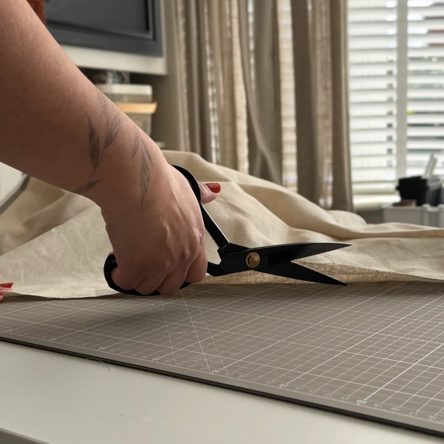 image of a woman's arm with scissors cutting fabric on a cutting table