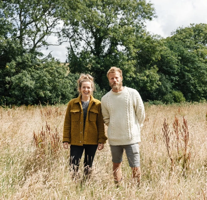 Florence and James Kennedy, founders of Petalon, smiling at the camera while stood in a field.