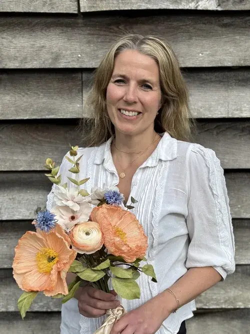 rachel standing and smiling, holding a bouquet of her flowers