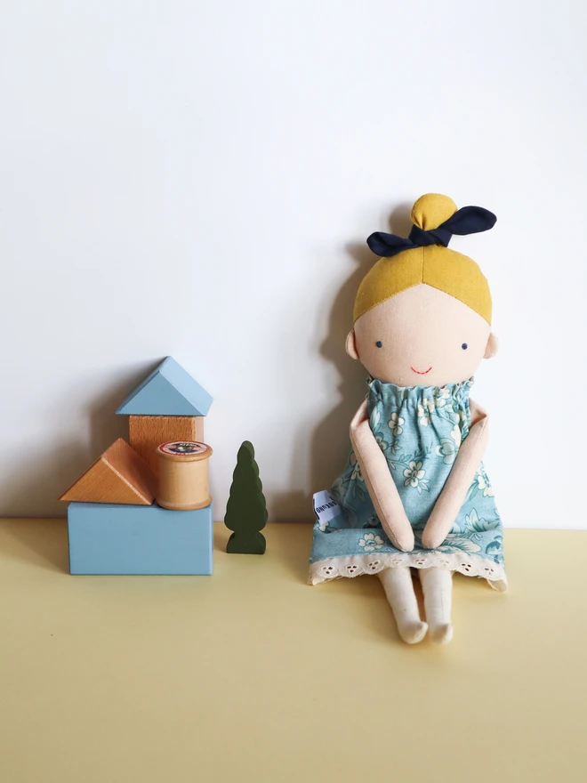 Cotton and linen doll with fair skin and blonde hair, wearing vintage inspired flower print in blue.