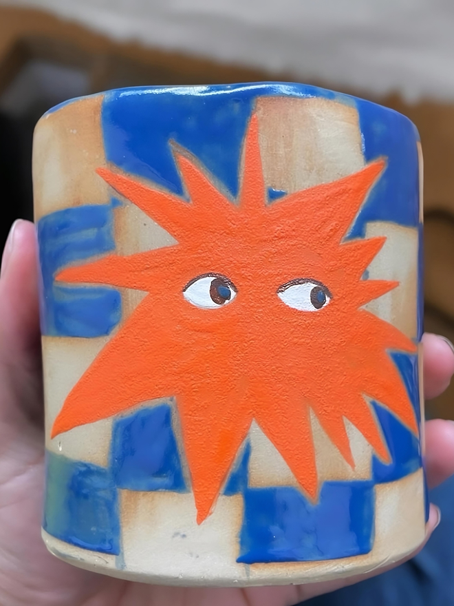 blue and white checked ceramic coffee cup with orange star emblem