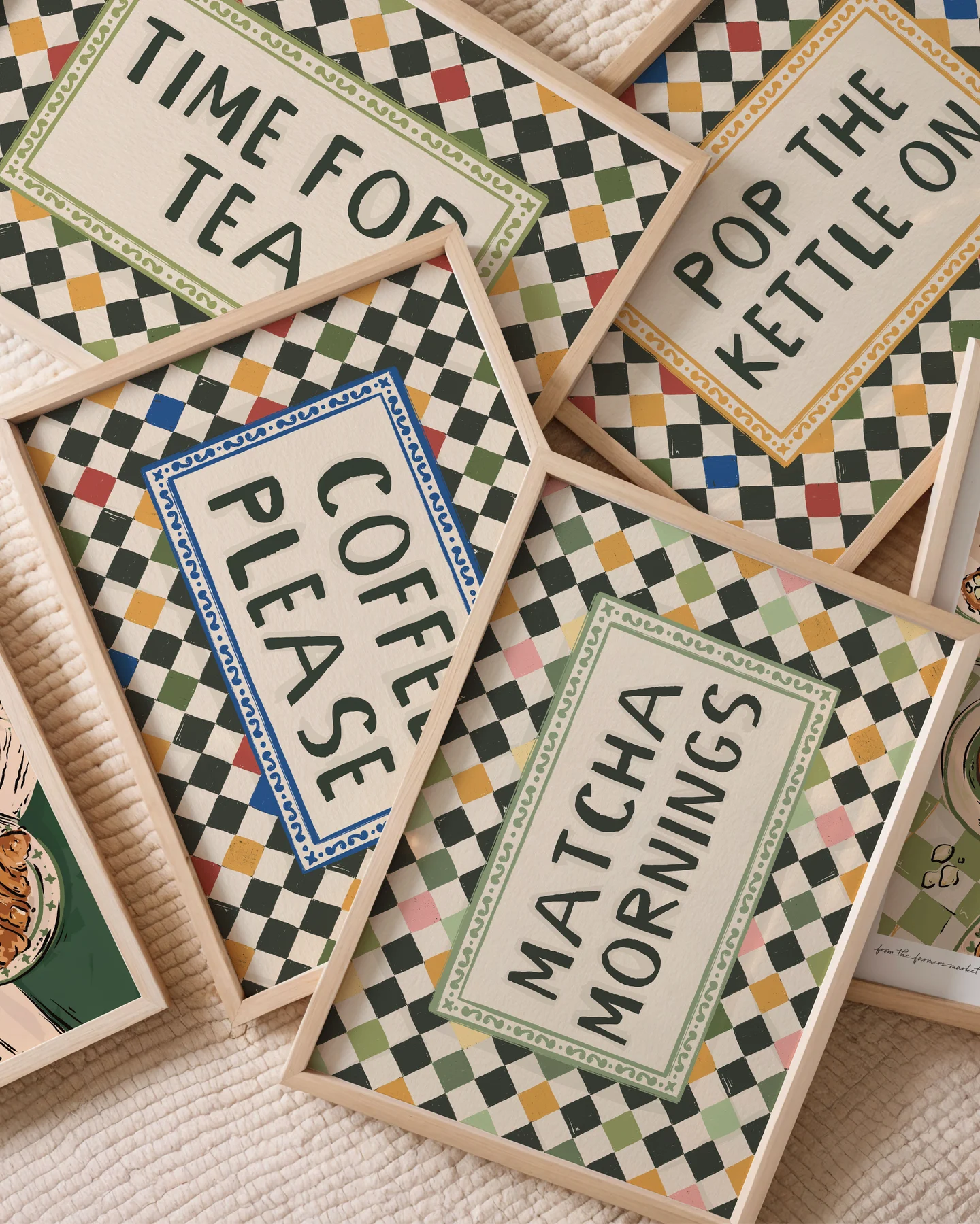 Flay lay of 5 framed prints, featuring colourful harlequin checkerboard designs with text, matcha mornings, pop the kettle on, coffee please and time for tea