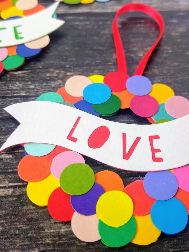 Colourful Christmas Bauble  with "Love" papercut in red on a white banner closeup