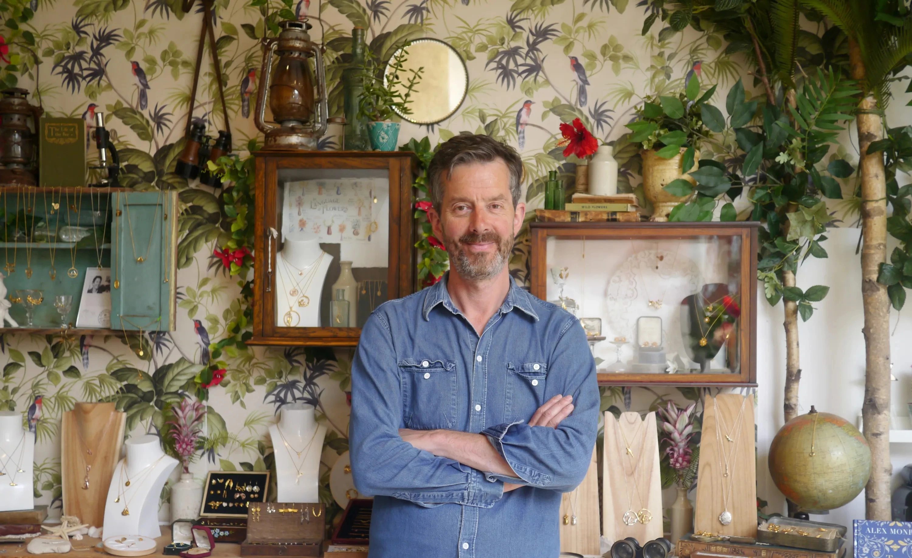 Alex Monroe, founder of Alex Monroe Jewellery, smiling at the camera in a denim shirt.