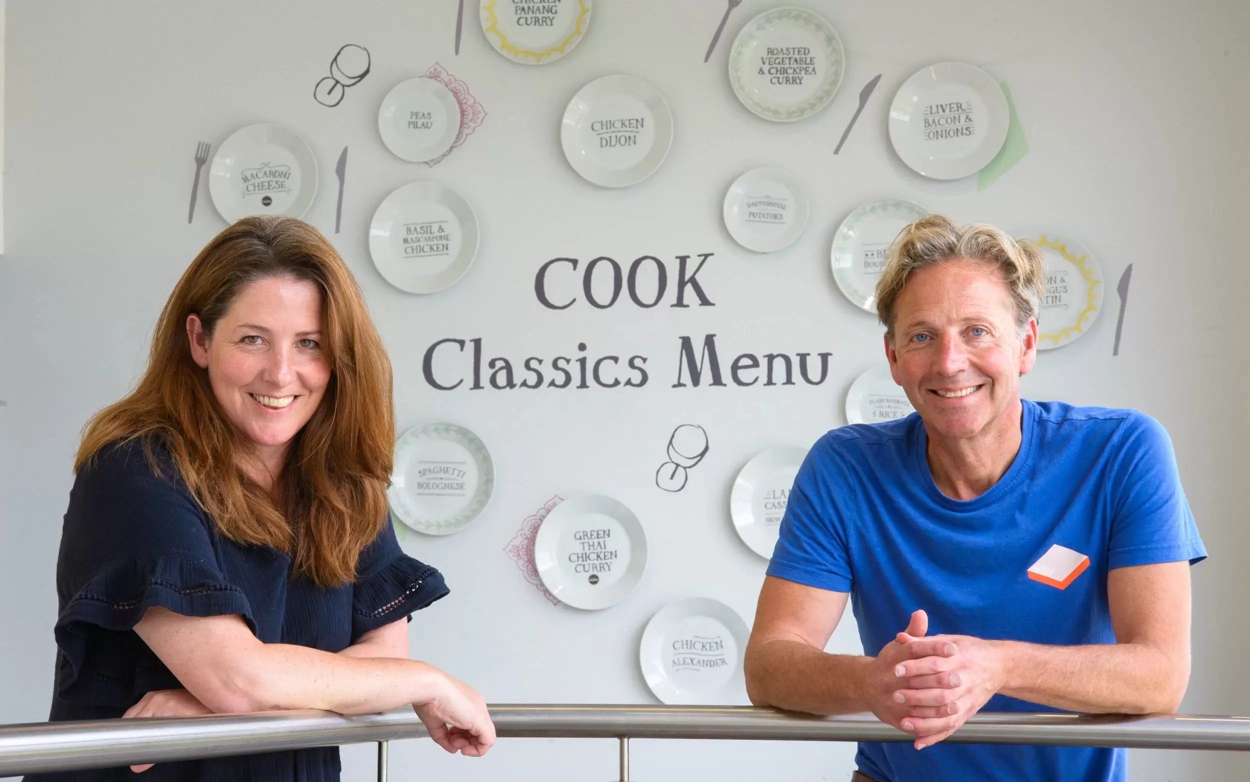 Edward Perry, founder of COOK, standing in front of a menu board.