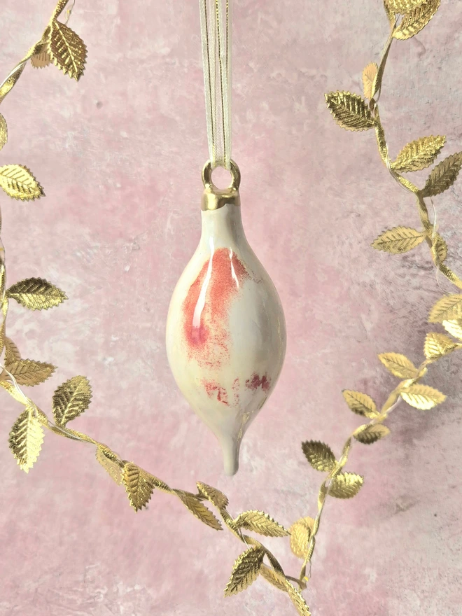 Ceramic christmas bauble decorations in a pearlescent glaze with white, cream and pink and gold, with silk ribbon and gold detailing. Photographed on a pearlescent serving dish with gold pears and christmas lights, gift, christmas, ceramics, pottery, christmas, decorations, christmas tree