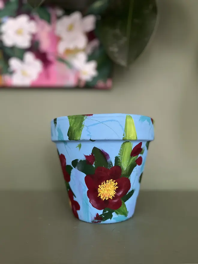 vibrant hand painted turquoise plant pot floral design deep red camellia flowers