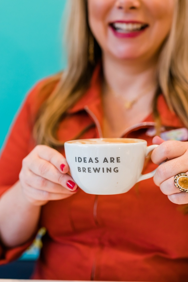Holly holding a coffee cup that says 'ideas are brewing'