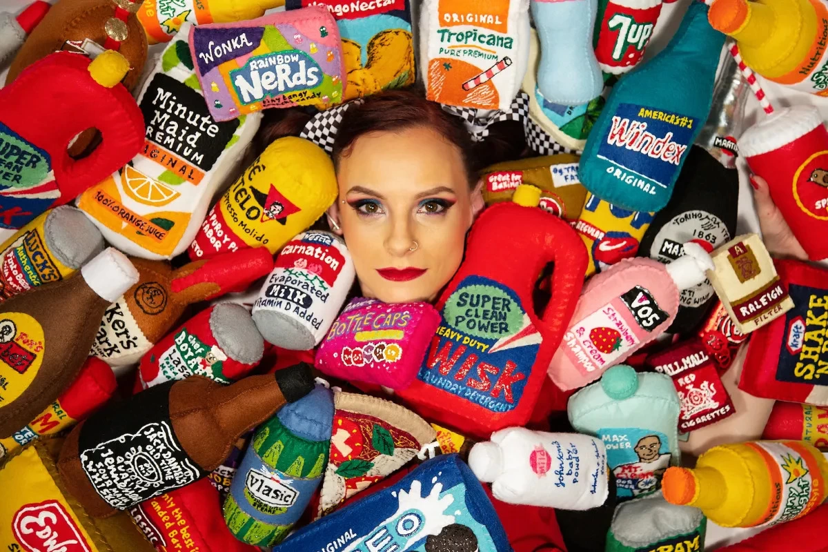 Lucy Sparrow, founder of Sew Your Soul, looking at the camera, surrounded by Sew Your Soul products.
