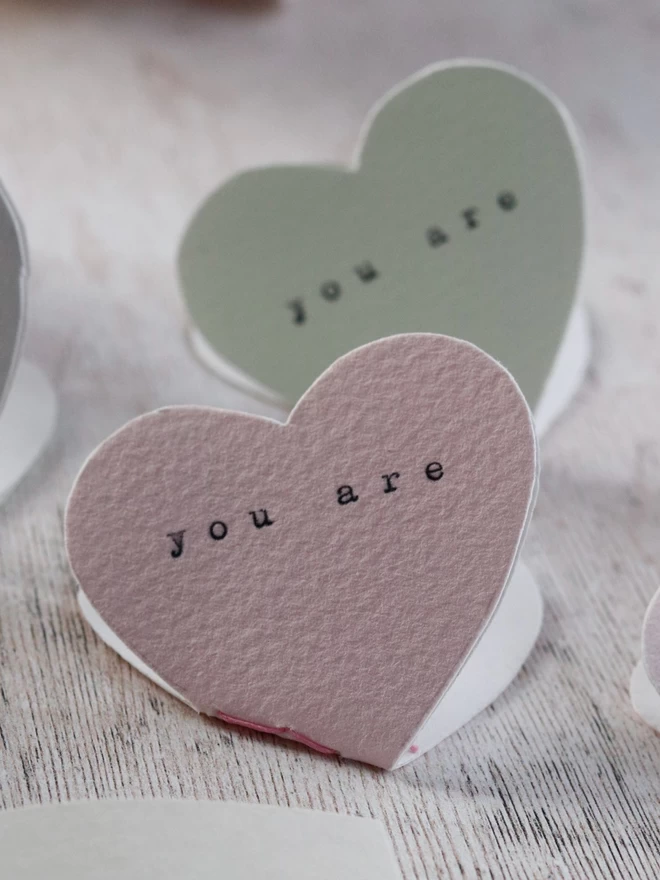mini heart shaped books in pale pink and pale green with 'you are' typed on the front