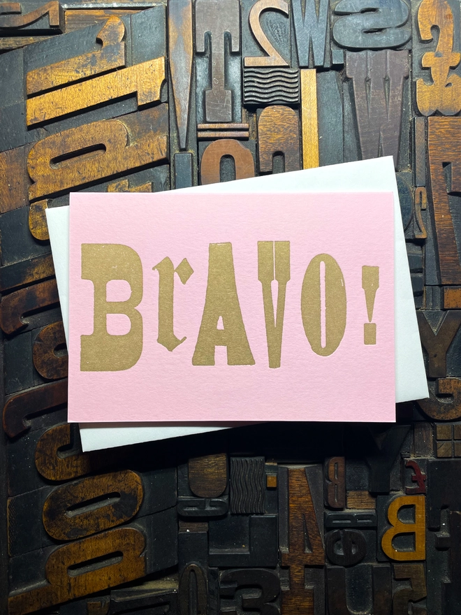 A congratulatory letterpress candy pink card featuring the deep impression word "BRAVO!"; in bold metallic gold letters with a set of colourful envelopes. Perfect for exam results and graduations and other celebrations and milestones.