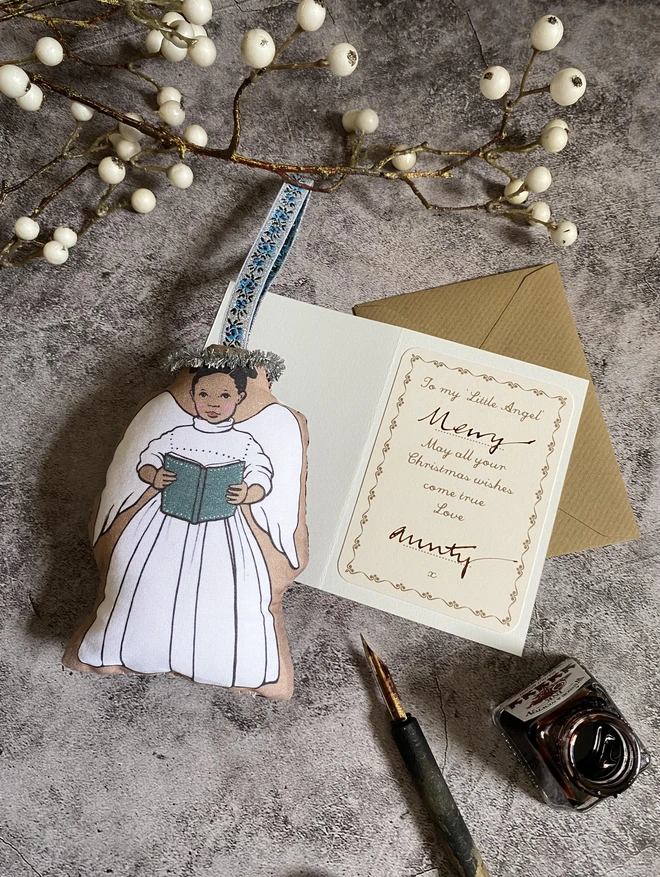 Christmas angel decoration laid next to a personalised little angel greeting card