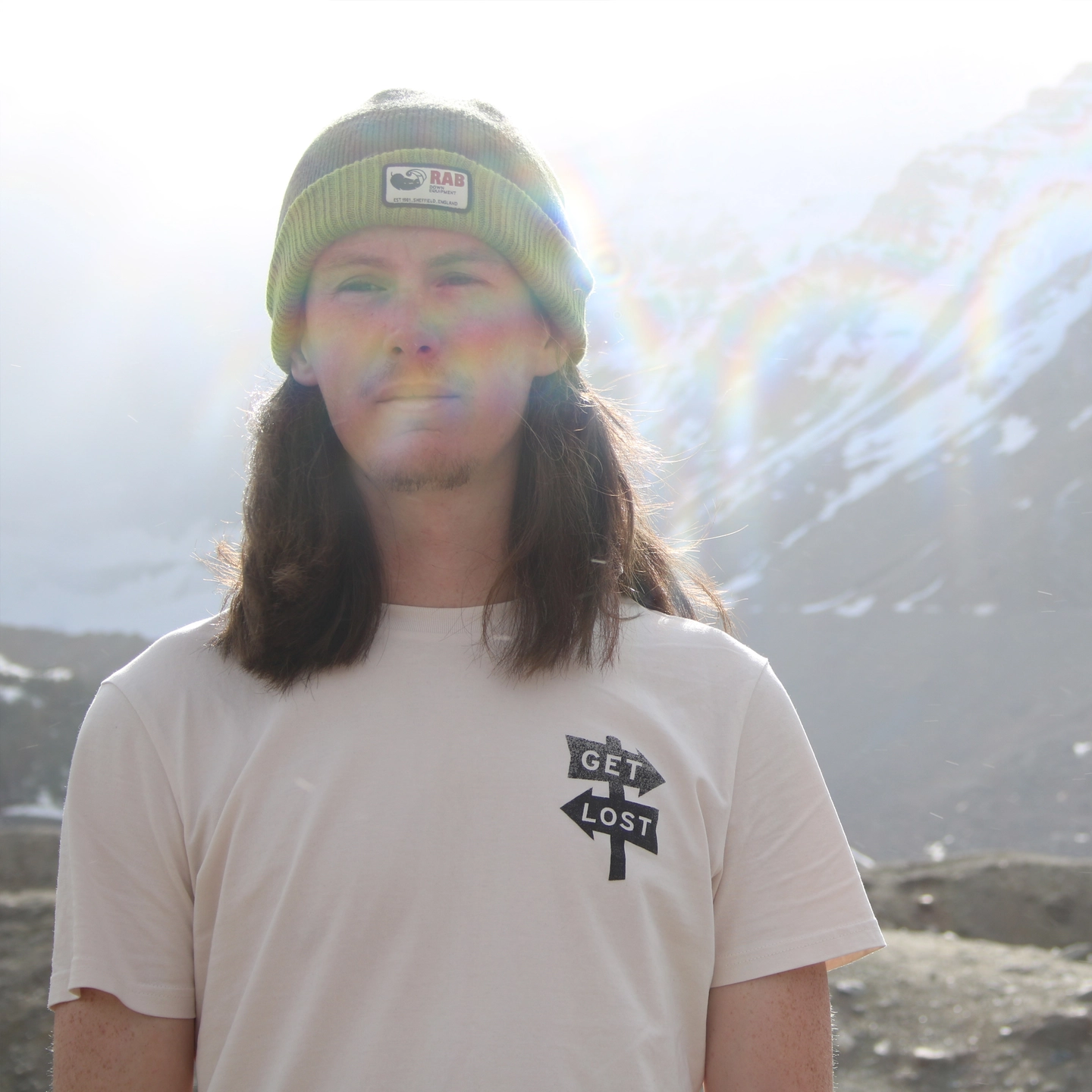 Man stood with hat on in front of mountains