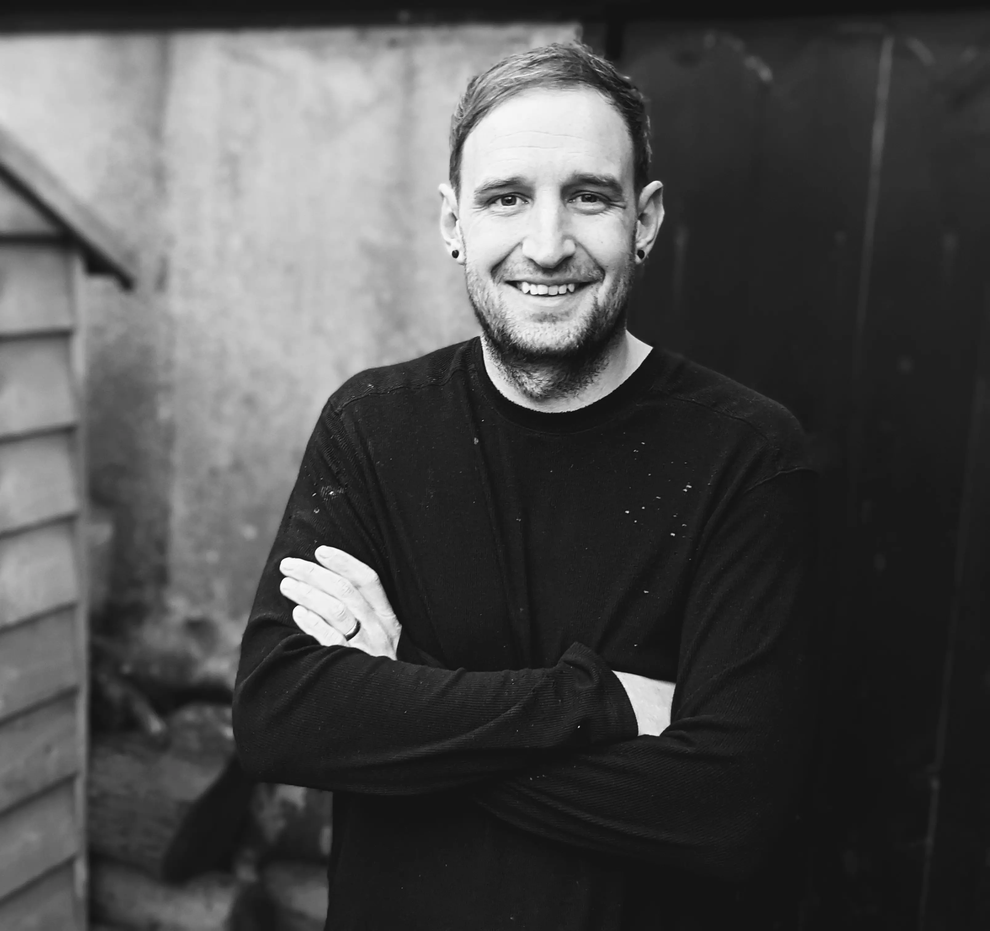 Something From The Turnery founder Joel Atkins stands smiling at the camera outside his workshop.