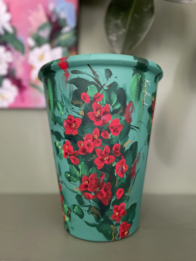 Hand painted tall deep green plant pot adorned with bright red quince flowers