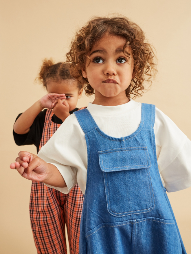 cool kids clothes on twin models one with oversized cotton t-shirt with dungarees