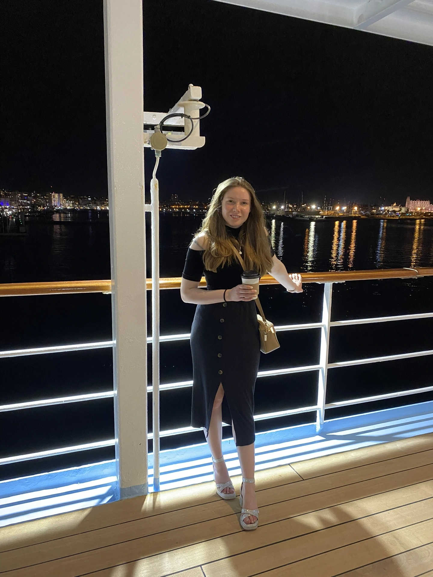 Holly dressed in black and silver heels on a cruise ship in the evening in Italy 