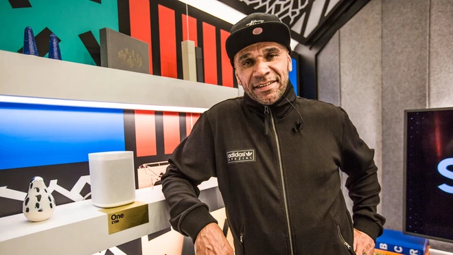Goldie MBE, DJ, artist & actor, smiling at the camera, wearing a black adidas jacket.