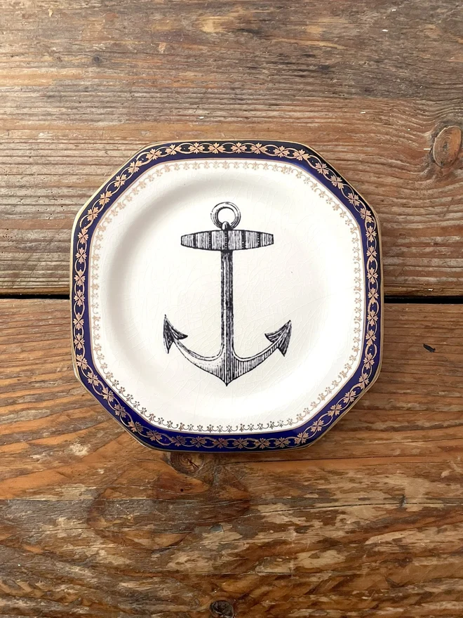 vintage plate with an ornate border, with a printed vintage illustration of an anchor in the middle 