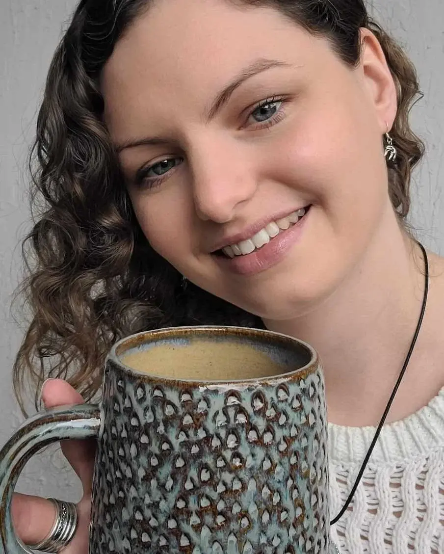 katie smiling and holding a seafoam mug
