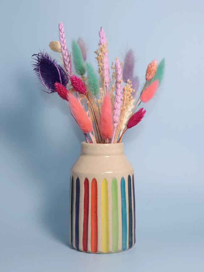Rainbow striped pottery bud vase with brightly coloured dried flowers