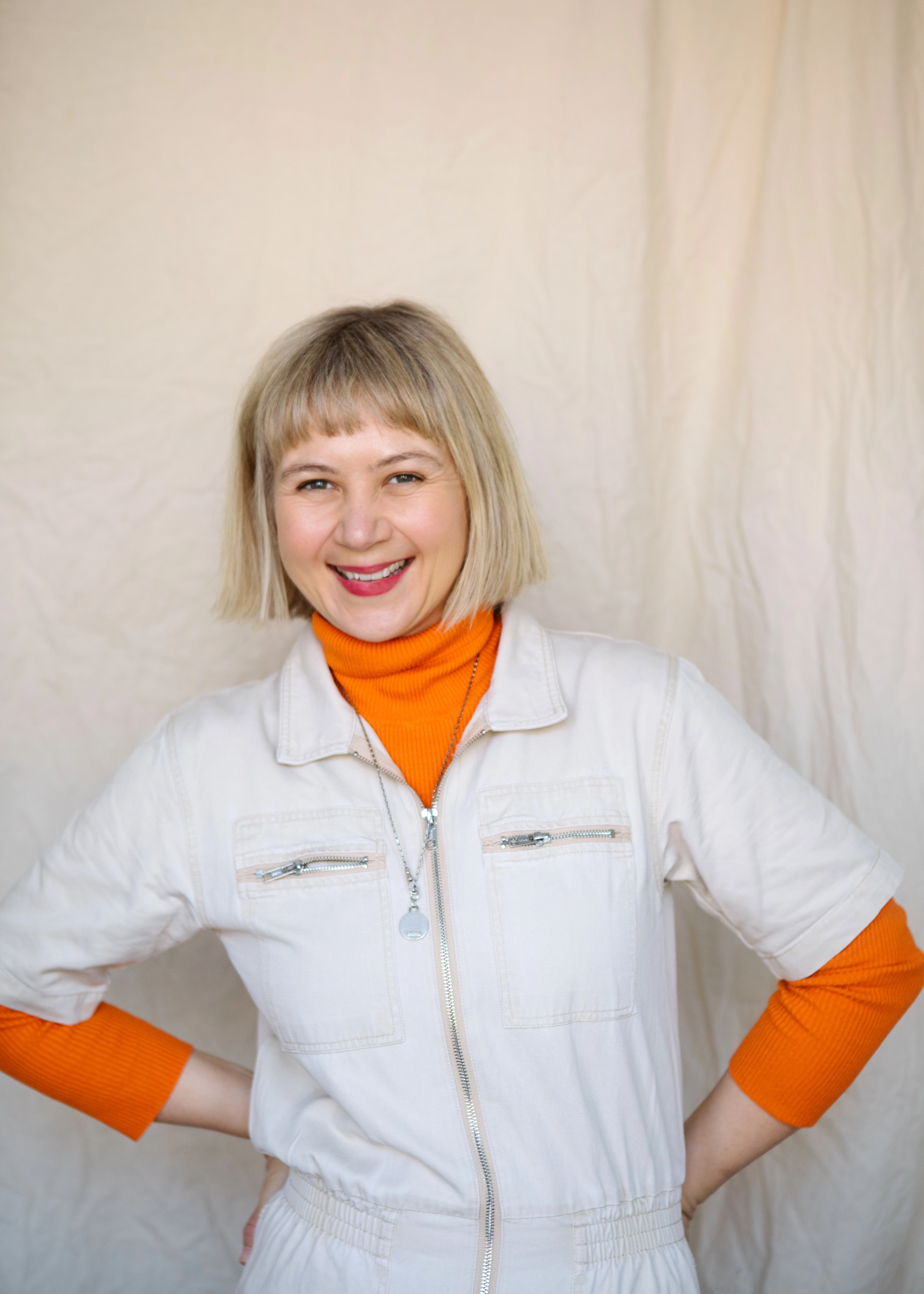 Portrait of a woman in an orange roll neck smiling at camera
