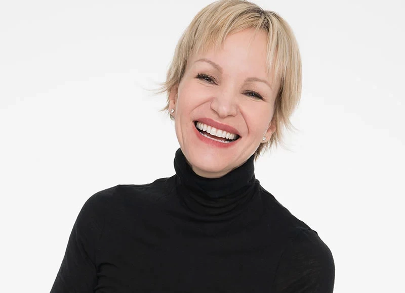 Marcia Kilgore, founder of Beauty Pie, smiling at the camera, wearing a black turtleneck top.