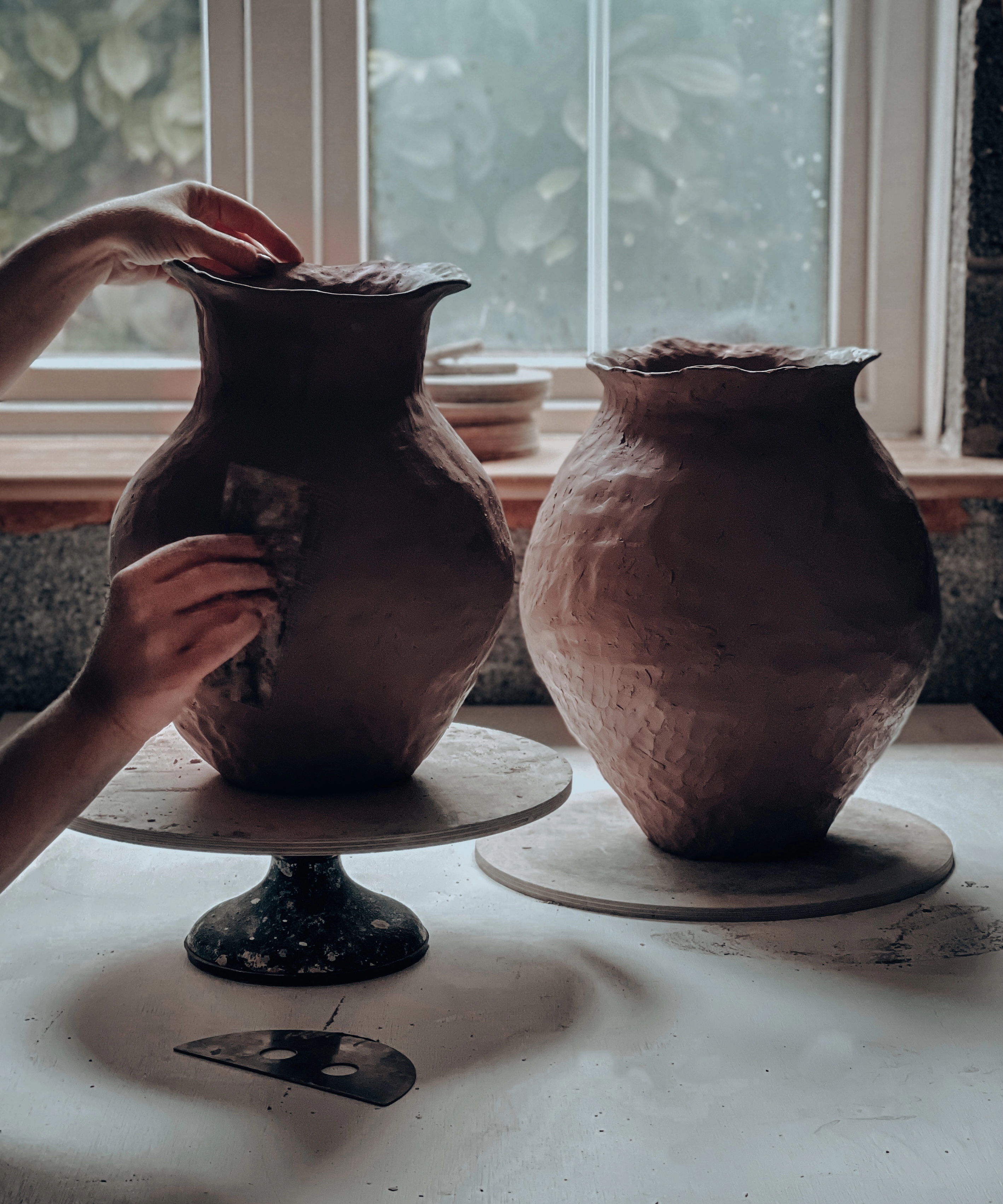 pottery hand making a vase in a pottery studio by the window